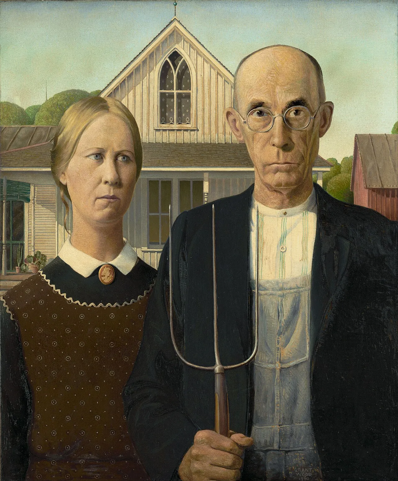 American Gothic: A stern man holding a pitchfork stands beside a woman in front of a Carpenter Gothic farmhouse.