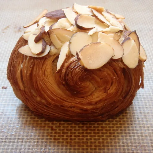 Croissant: A crescent-shaped pastry with overlapping layers, browned edges, and a soft broken surface.