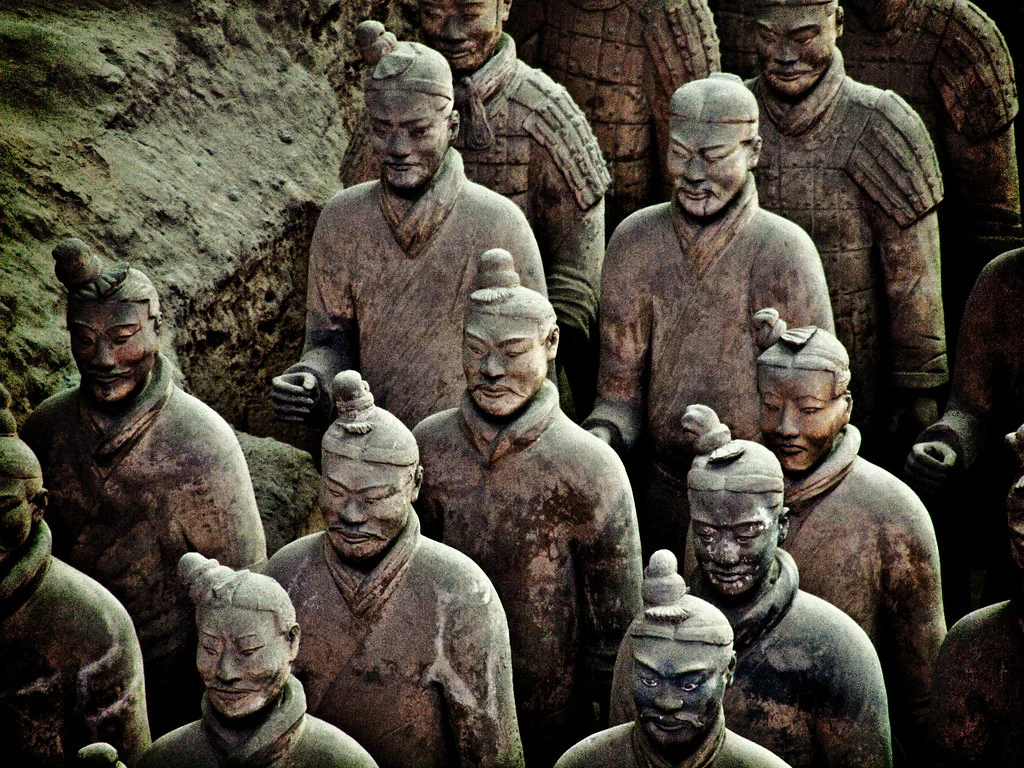 Terracotta Warrior: A life-sized clay figure with a composed face, layered clothing, and traces of surrounding figures.