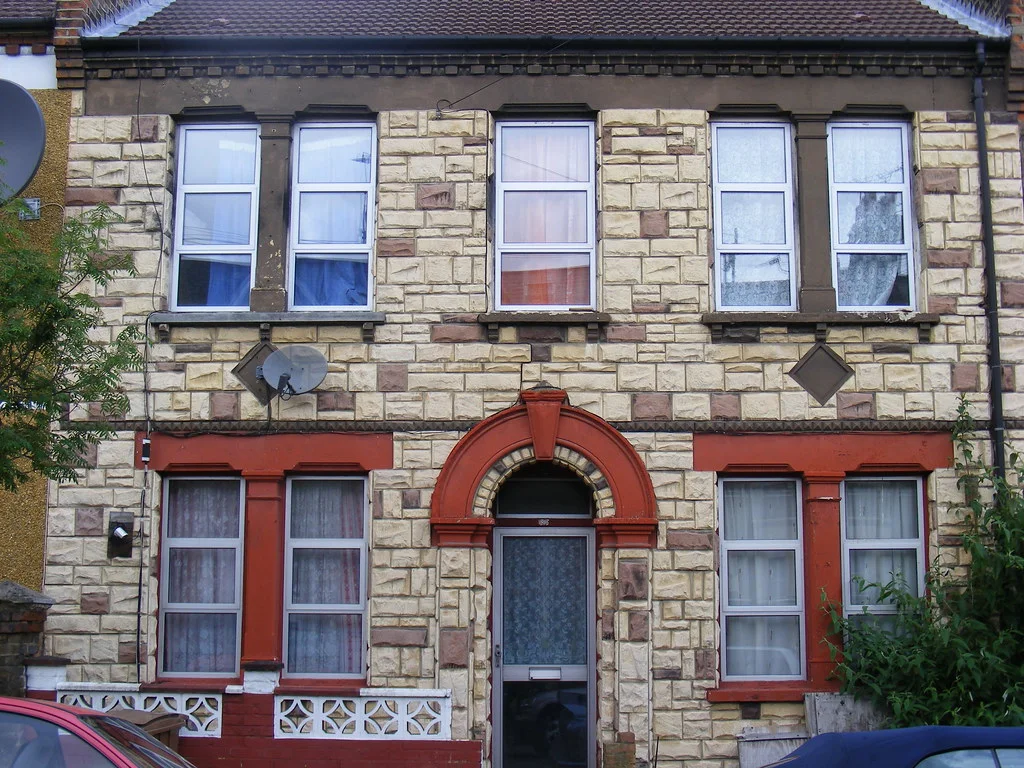Victorian London Terrace: A row of brick homes with bay windows, steps, repeated doors, and window rhythms.